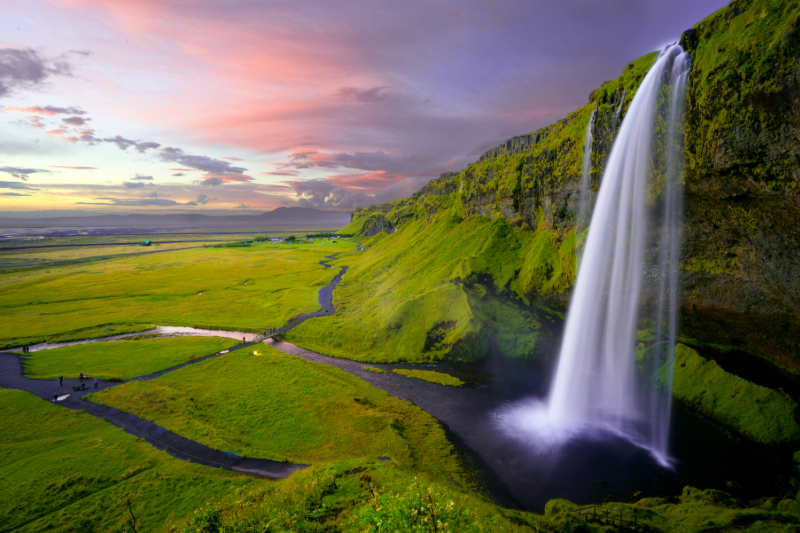 Majestätischer Wasserfall Seljalandsfoss in Island bei Sonnenuntergang vor grüner Landschaft.