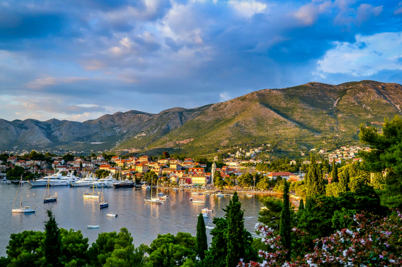 Hafenblick auf Cavtat an der Adriaküste – farbenfrohe Häuser vor grüner Bergkulisse.