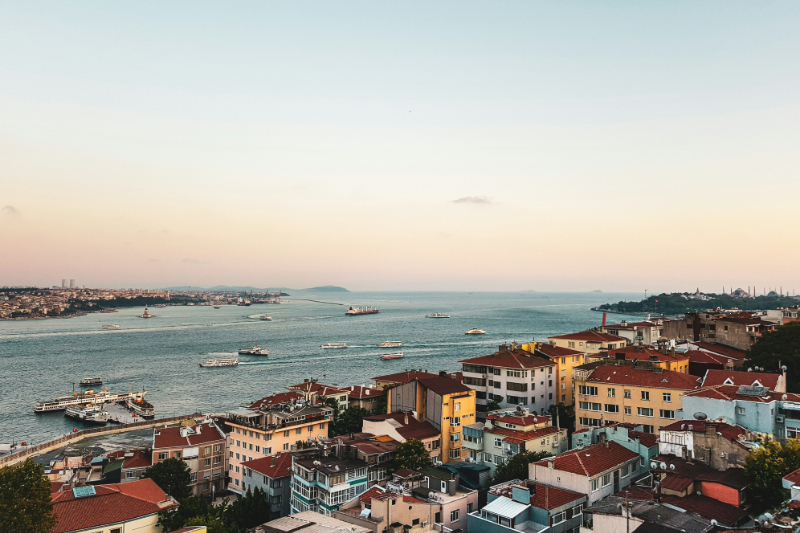 Ausblick über den Bosporus in Istanbul mit historischen Häusern und Fähren bei Sonnenuntergang.